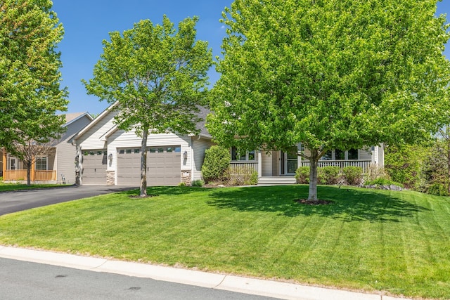 obstructed view of property featuring a garage, asphalt driveway, a front lawn, and covered porch