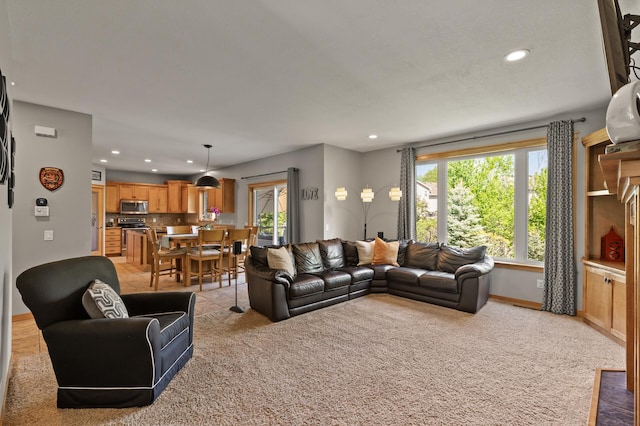 living room with recessed lighting, light colored carpet, and baseboards