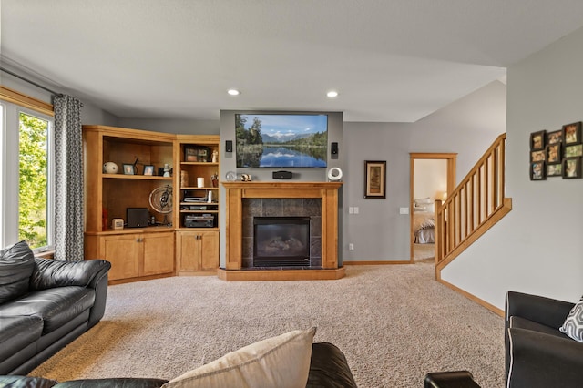 carpeted living area with stairs, a tiled fireplace, baseboards, and recessed lighting
