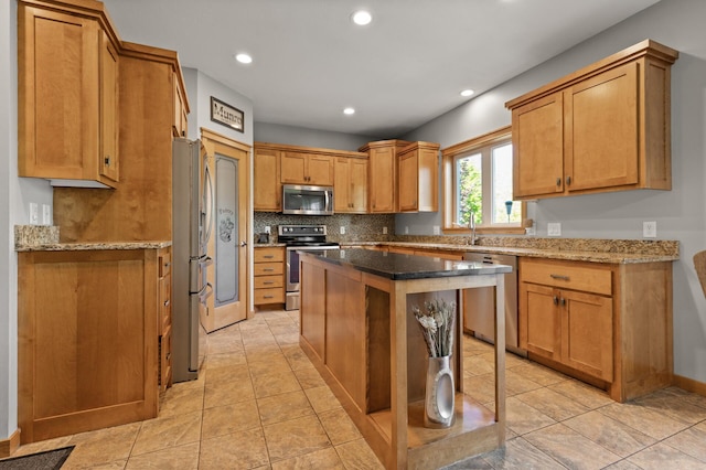 kitchen with appliances with stainless steel finishes, decorative backsplash, recessed lighting, a kitchen island, and stone counters