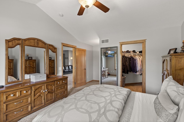 bedroom with light colored carpet, lofted ceiling, a closet, a walk in closet, and a ceiling fan