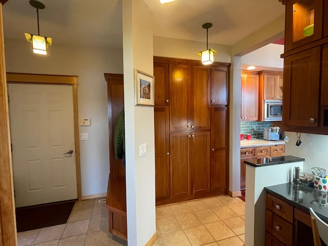 13966 346th Ct, Lindstrom, MN 55045 - kitchen featuring hanging light fixtures, tasteful backsplash, brown cabinets, stainless steel microwave, and light tile patterned flooring