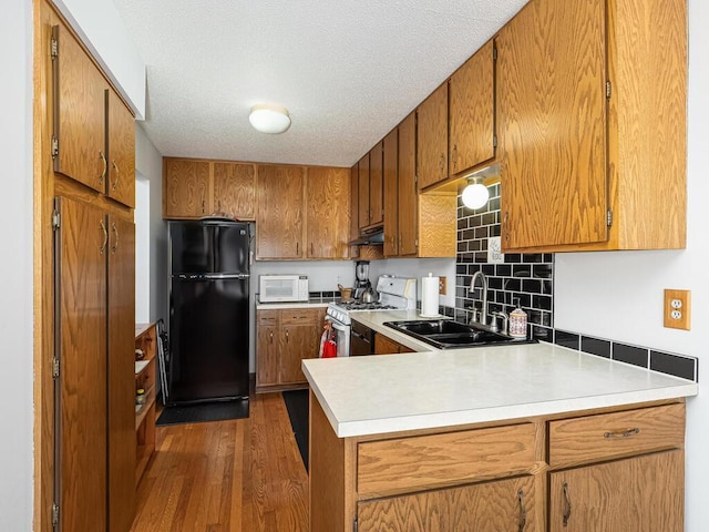15722 Griffon Ct, Apple Valley, MN 55124 - kitchen featuring white appliances, a sink, under cabinet range hood, brown cabinets, and a textured ceiling