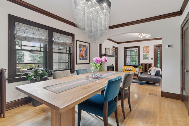 1295 Fairmount Ave, Saint Paul, MN 55105 - dining area with radiator, a chandelier, light wood-style flooring, arched walkways, and crown molding