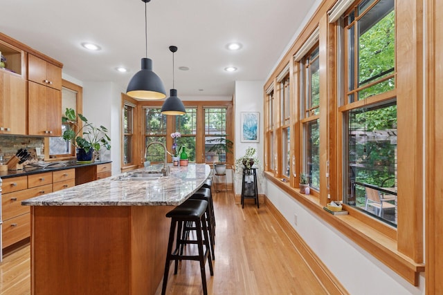 1295 Fairmount Ave, Saint Paul, MN 55105 - kitchen featuring recessed lighting, light wood-style floors, tasteful backsplash, a breakfast bar area, and hanging light fixtures
