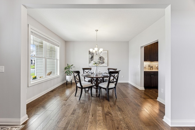dining area with a chandelier, baseboards, and dark wood finished floors