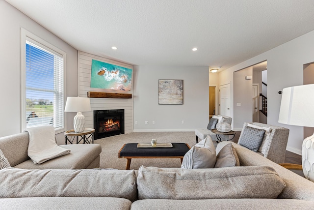 living area featuring a large fireplace, baseboards, recessed lighting, and a textured ceiling