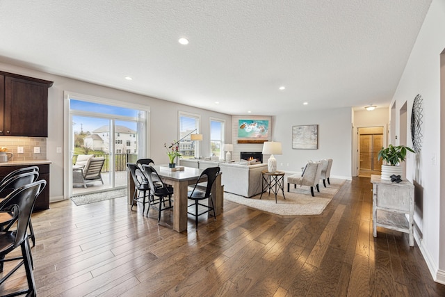 dining area featuring recessed lighting, a textured ceiling, a lit fireplace, and hardwood / wood-style flooring