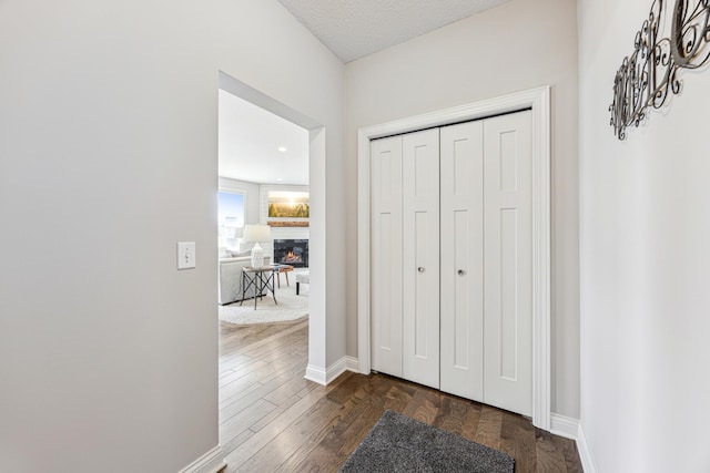 corridor featuring baseboards and dark wood finished floors
