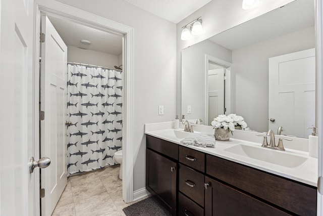 full bathroom featuring double vanity, a sink, a shower with shower curtain, and toilet