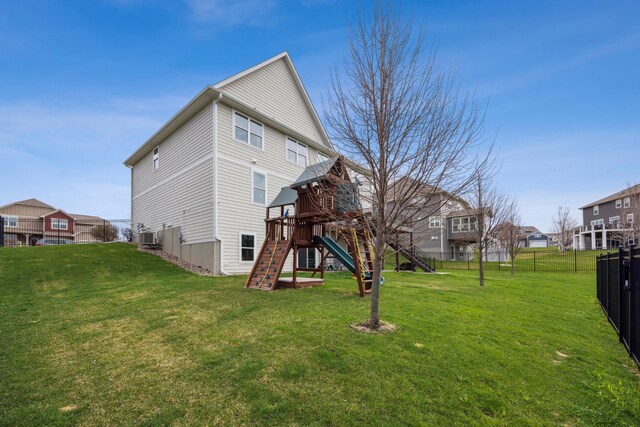 back of house featuring a lawn, a playground, fence, and central AC
