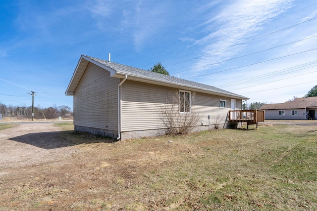 view of side of home with a wooden deck and a lawn