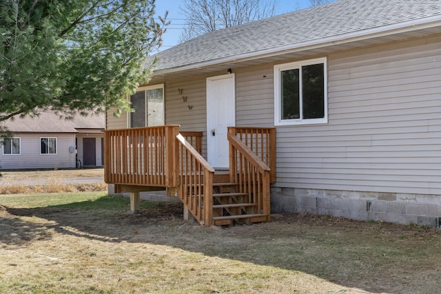 property entrance featuring a lawn and a shingled roof