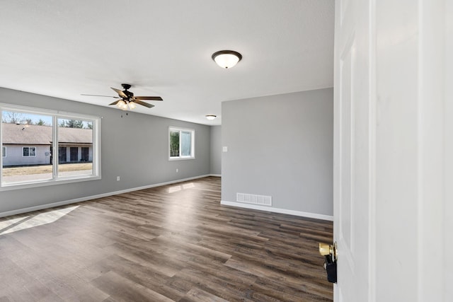unfurnished room with ceiling fan, baseboards, dark wood-style flooring, and visible vents