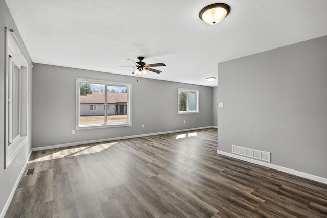 interior space with dark wood-style floors, baseboards, a ceiling fan, and visible vents