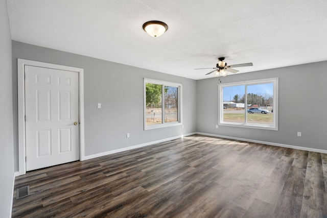 unfurnished room featuring a textured ceiling, ceiling fan, visible vents, baseboards, and dark wood-style floors