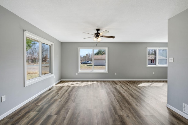 spare room with dark wood-type flooring, plenty of natural light, a ceiling fan, and baseboards