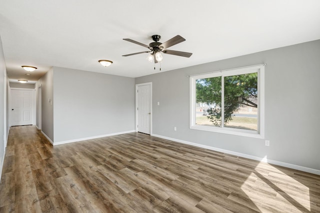 empty room featuring wood finished floors, a ceiling fan, and baseboards