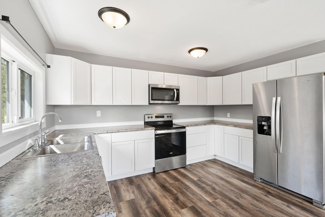 kitchen featuring white cabinets, stainless steel appliances, a sink, and dark wood-type flooring