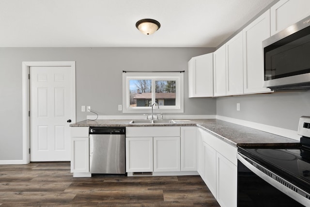 kitchen featuring white cabinets, dark wood finished floors, appliances with stainless steel finishes, and a sink