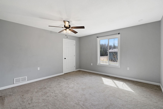 spare room with baseboards, a ceiling fan, visible vents, and carpet