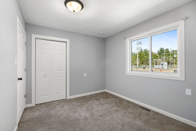 unfurnished bedroom with a closet, carpet, visible vents, and baseboards
