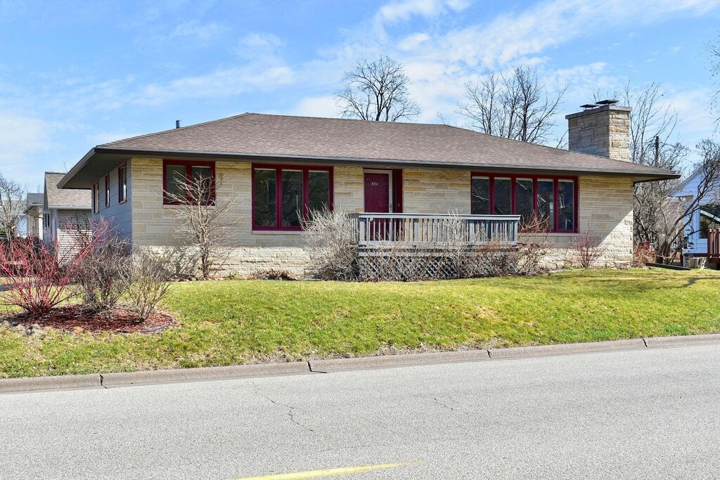 324 Lake St, Winona, MN 55987 - ranch-style house with stone siding, roof with shingles, a chimney, a front lawn, and a porch