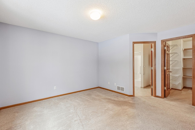 3621 Lansing Ave NE, Saint Michael, MN 55376 - unfurnished bedroom with light colored carpet, a spacious closet, a textured ceiling, a closet, and ensuite bathroom