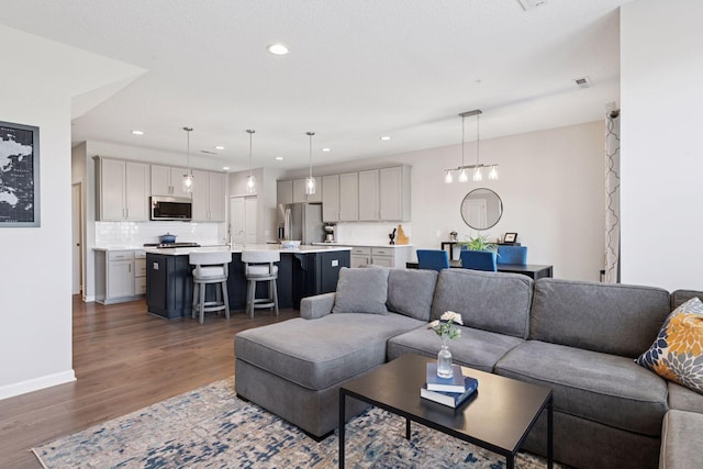 living area with baseboards, recessed lighting, and dark wood-style flooring