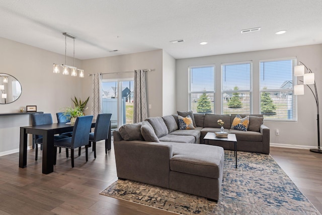 living area featuring visible vents, a healthy amount of sunlight, and dark wood-style flooring
