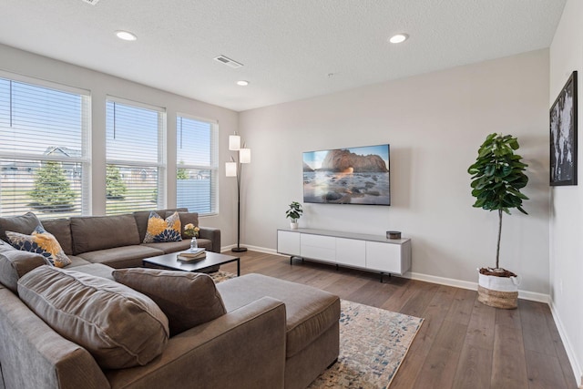 living area with recessed lighting, visible vents, wood-type flooring, baseboards, and a textured ceiling