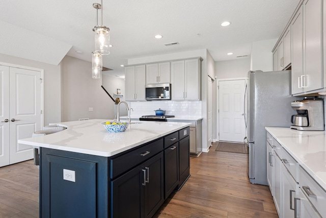 kitchen featuring stainless steel microwave, decorative backsplash, dark wood-style flooring, and a sink