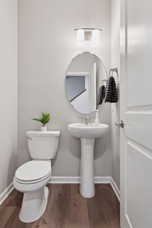 bathroom with baseboards, toilet, and wood finished floors
