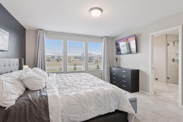 bedroom with a textured ceiling, baseboards, visible vents, light colored carpet, and connected bathroom