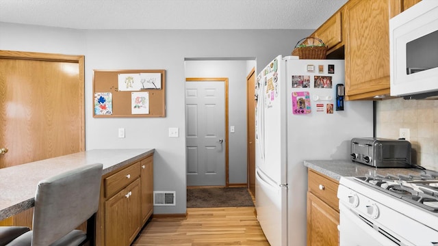 112 Sandpiper Cir, Hastings, MN 55033 - kitchen with white appliances, light wood-style flooring, decorative backsplash, light countertops, and brown cabinets