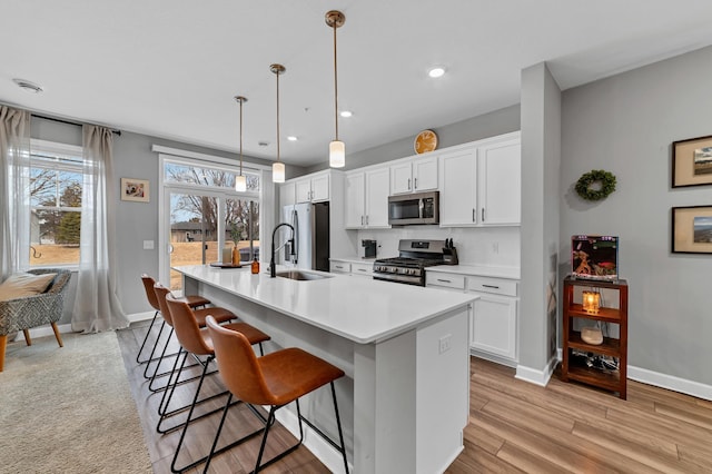 22962 Hazel Ln, Rogers, MN 55374 - kitchen with appliances with stainless steel finishes, a kitchen island with sink, a breakfast bar area, baseboards, and recessed lighting