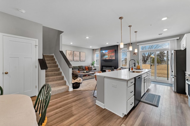 22962 Hazel Ln, Rogers, MN 55374 - kitchen with appliances with stainless steel finishes, a sink, white cabinetry, an island with sink, and light wood-type flooring