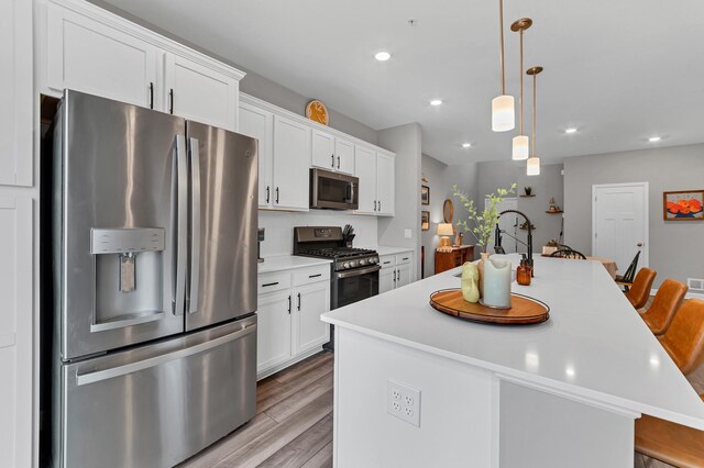 22962 Hazel Ln, Rogers, MN 55374 - kitchen featuring stainless steel appliances, a center island, light wood-style floors, light countertops, and white cabinets