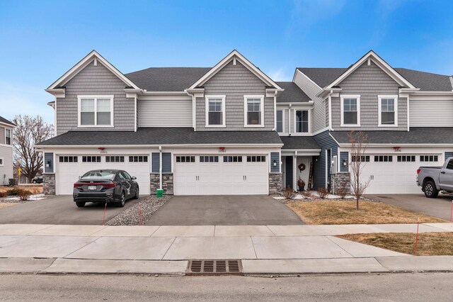 22962 Hazel Ln, Rogers, MN 55374 - view of property featuring stone siding, driveway, a garage, and a shingled roof