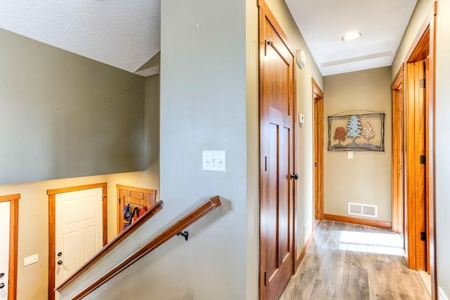 hall featuring an upstairs landing, baseboards, light wood-style floors, and visible vents