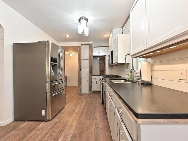 21327 Keyview Rd, Grand Rapids, MN 55744 - kitchen featuring appliances with stainless steel finishes, dark countertops, wood finished floors, a sink, and recessed lighting