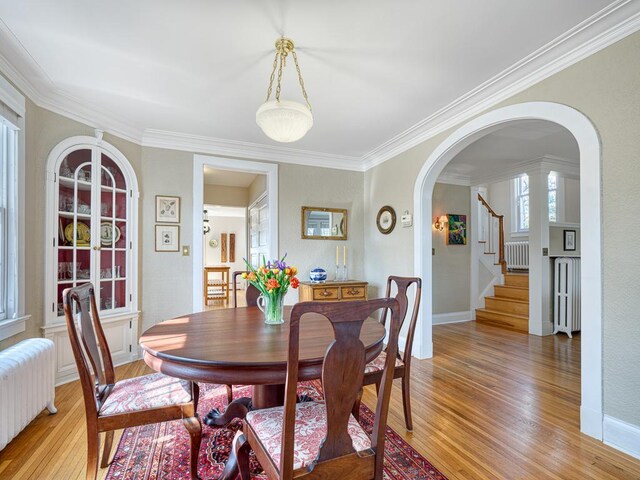 25 Benhill Rd, Saint Paul, MN 55105 - dining area featuring radiator, light wood-style floors, arched walkways, crown molding, and stairs