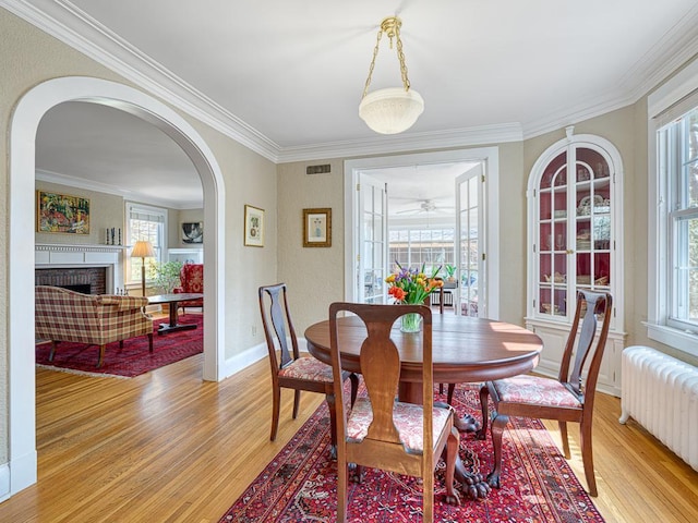 25 Benhill Rd, Saint Paul, MN 55105 - dining space featuring radiator heating unit, plenty of natural light, light wood-style flooring, ornamental molding, and arched walkways