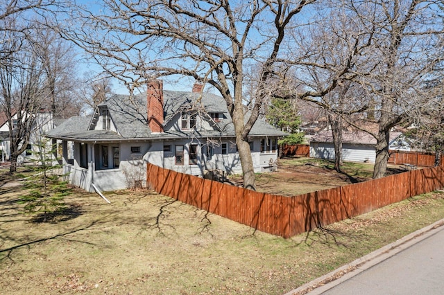 rear view of house featuring a chimney, a shingled roof, and fence private yard