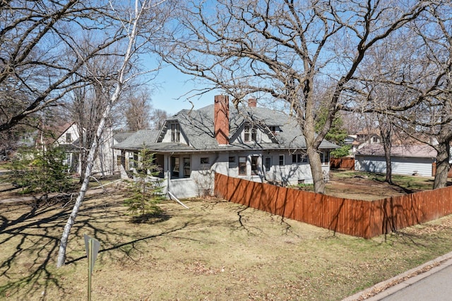 rear view of property featuring a chimney and fence