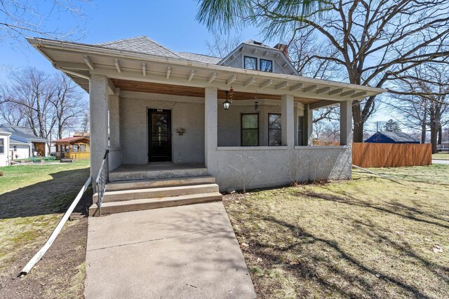 property entrance with a porch, fence, roof with shingles, and stucco siding