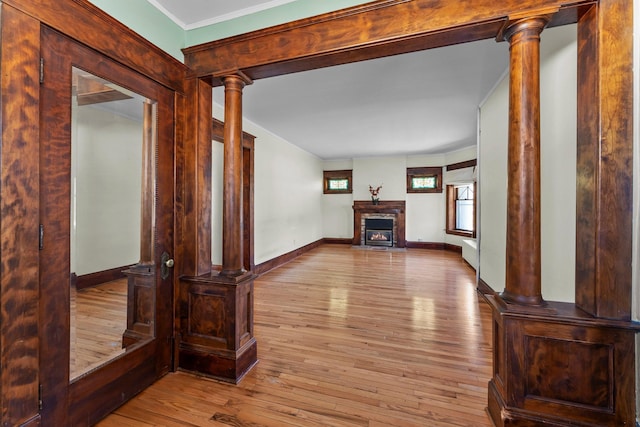 unfurnished living room with baseboards, crown molding, a glass covered fireplace, and hardwood / wood-style floors