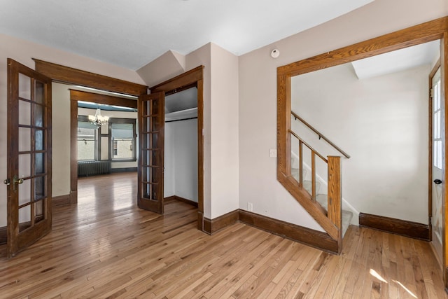 interior space featuring baseboards, french doors, a chandelier, and hardwood / wood-style floors