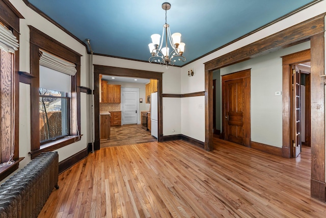 unfurnished dining area featuring radiator, light wood-style flooring, baseboards, and an inviting chandelier