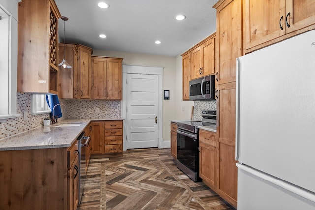 kitchen with a sink, tasteful backsplash, recessed lighting, light stone countertops, and appliances with stainless steel finishes